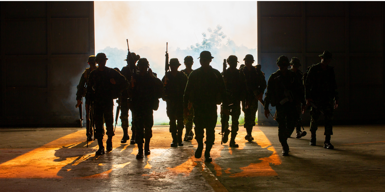 Service members silhouetted in a hangar doorway